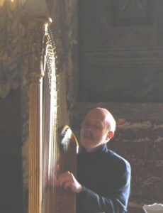 Photo of a man playing an ornate old pedal harp
